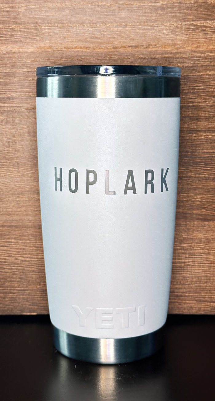White insulated tumbler with 'HOPLARK' branding on a wooden surface